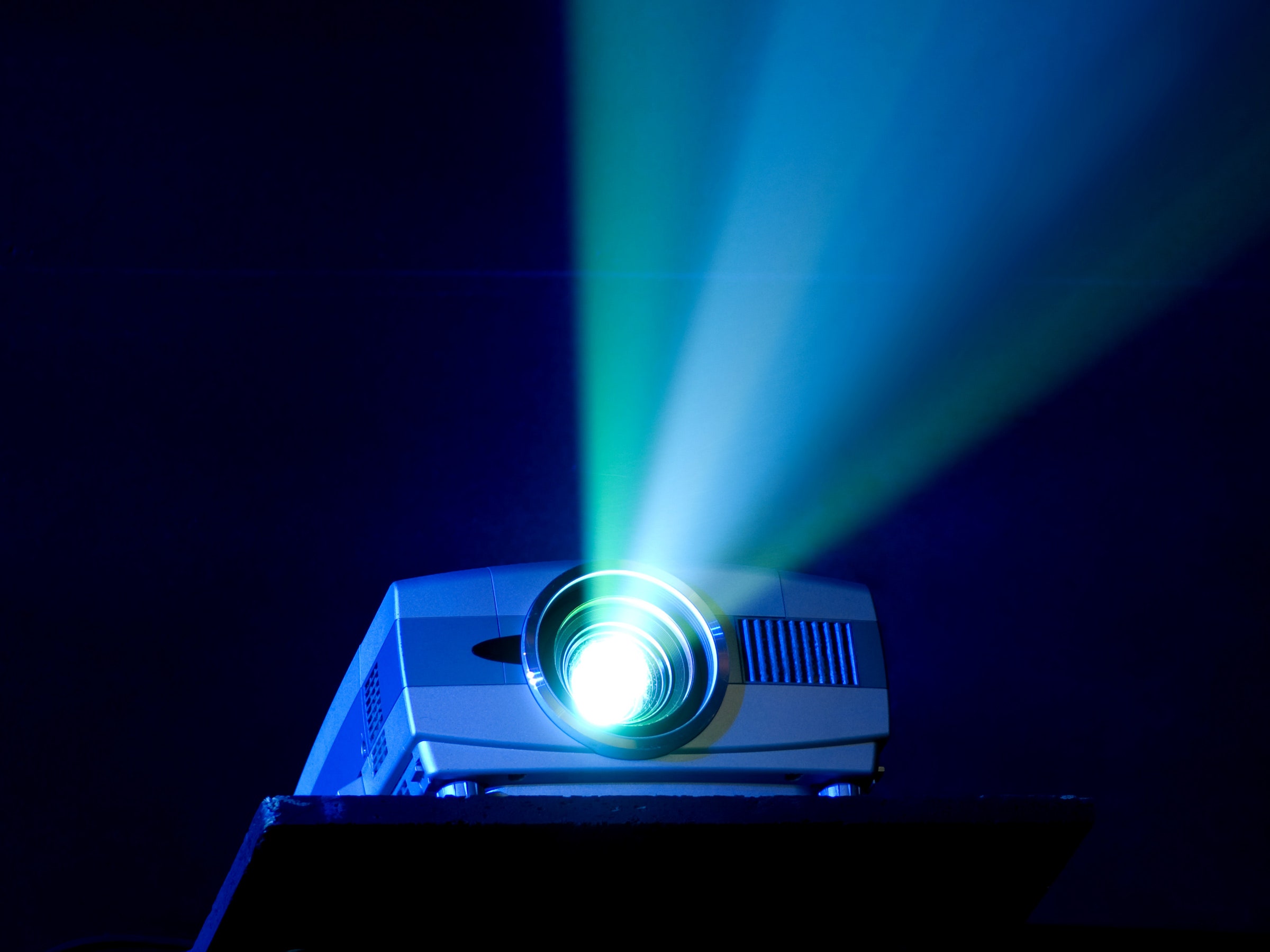 A projector shooting light out of its lens on a blue background