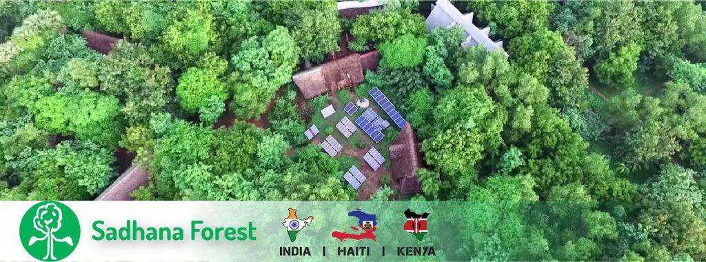 Picture of sadhana forest an aerial view of forest with solar panels in between along with huts.